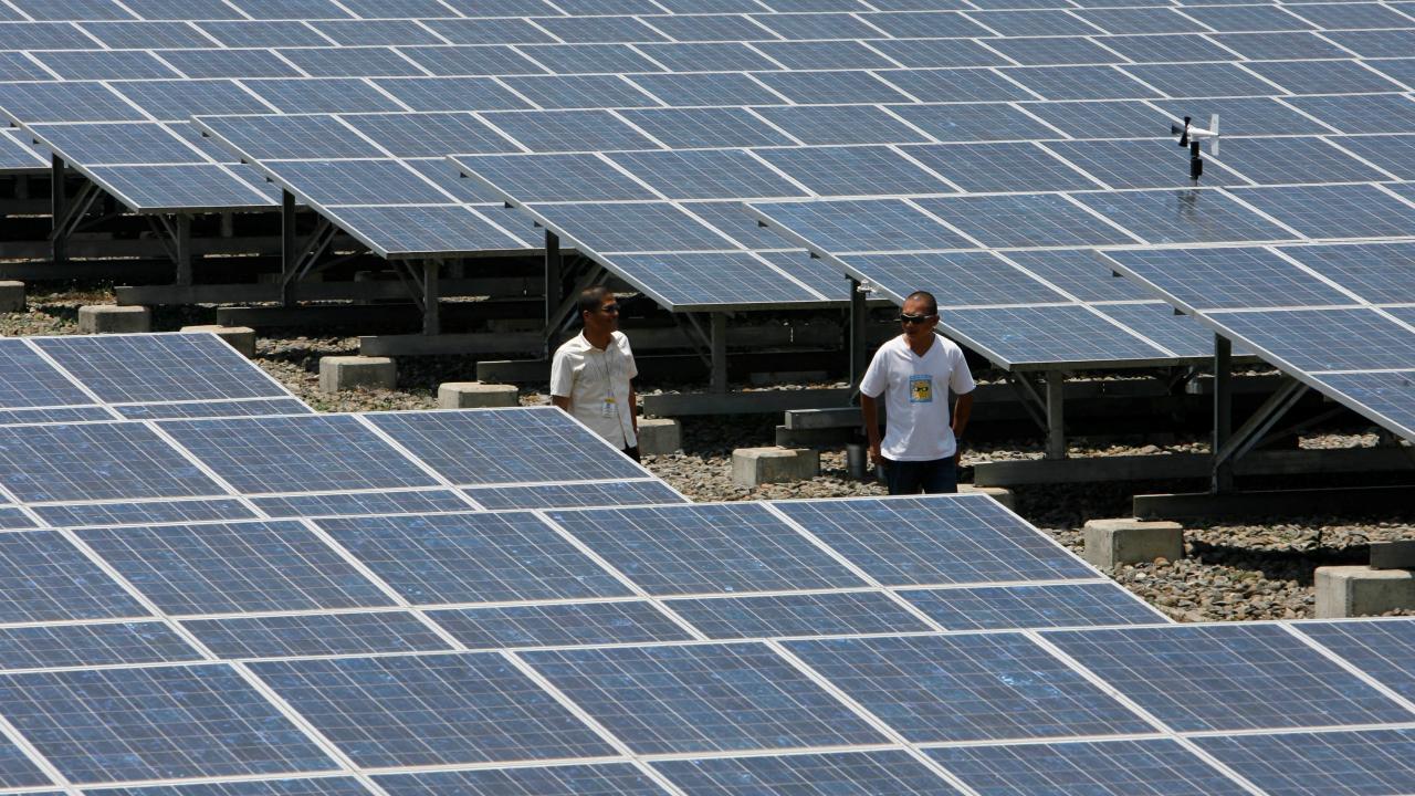 Cecilio Sumaoy (izq.), director de planta de Cagayan Electric Power and Light Co. Inc. (CEPALCO), pasa por delante de un conjunto de paneles solares de dos hectáreas instalado en el pueblo de Indahag, en Cagayan De Oro, al sur de Filipinas.