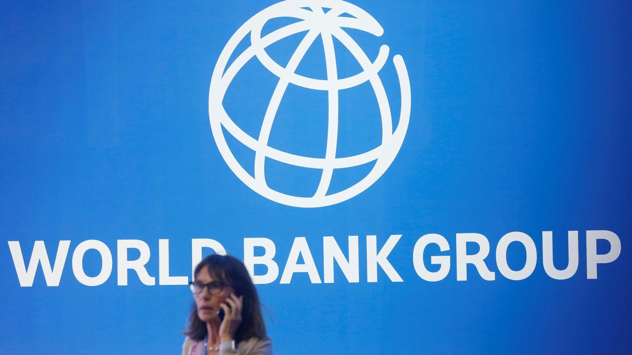 A participant stands near a logo of World Bank at the International Monetary Fund - World Bank Annual Meeting 2018 in Nusa Dua, Bali, Indonesia.