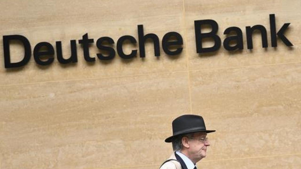Hombre caminando frente a logo de Deutsche Bank