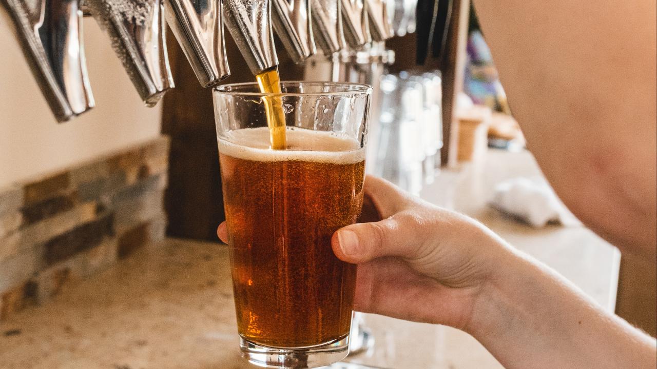 Persona sirviendo un vaso de cerveza desde un dispensador.