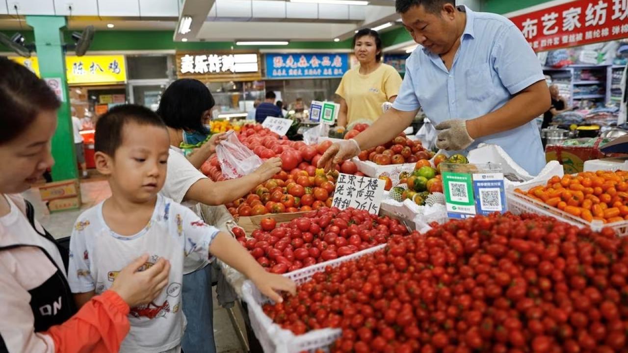 Customers select tomatoes at a stall inside a morning market in Beijing, China August 9, 2023. REUTERS/Tingshu Wang
