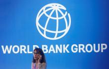 A participant stands near a logo of World Bank at the International Monetary Fund - World Bank Annual Meeting 2018 in Nusa Dua, Bali, Indonesia.